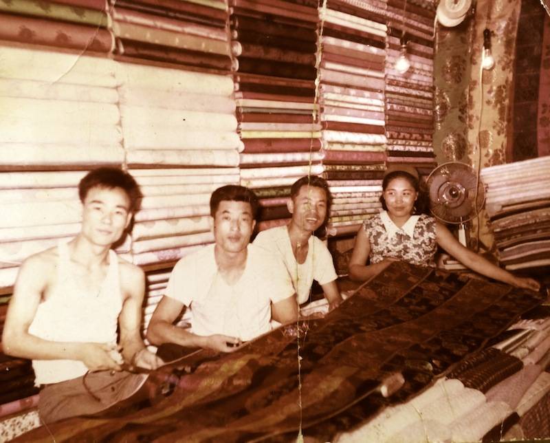 LEEHWA HISTORY. GROUP OF PEOPLE SITTING WITH FABRICS. 