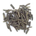 A pile of dark long pepper kernels that are dotted with light yellow dots