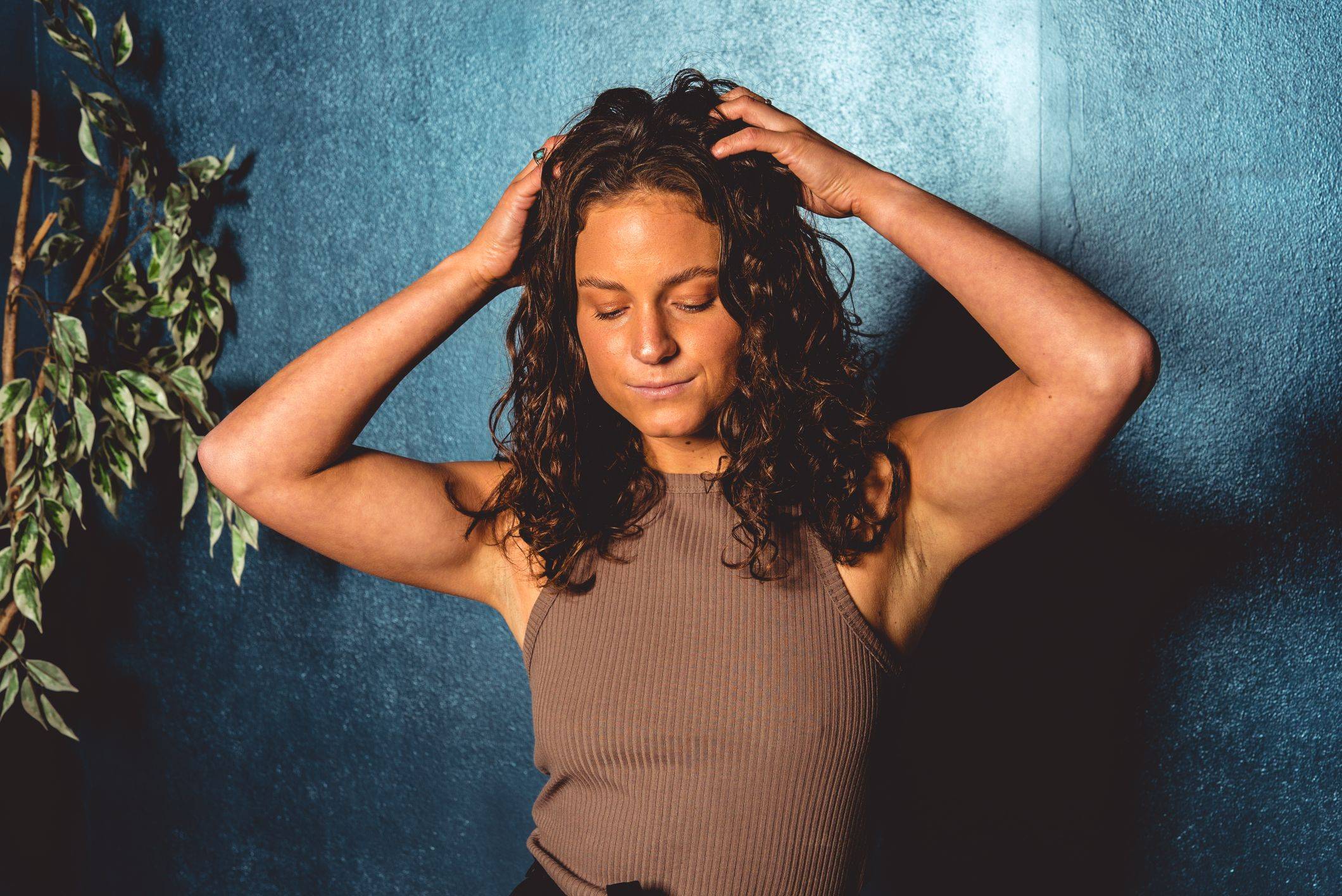 Image of a women with a wavy hair and hands on her head