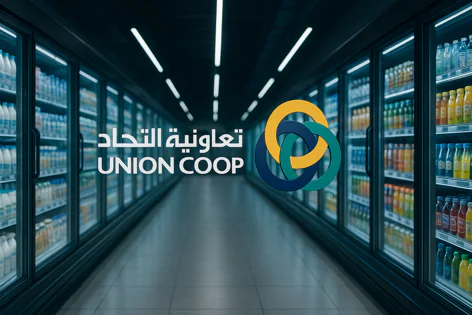 Union Coop logo and name overlayed on a dark supermarket aisle with refrigerated cases full of milk, juices, and other bottled drinks.