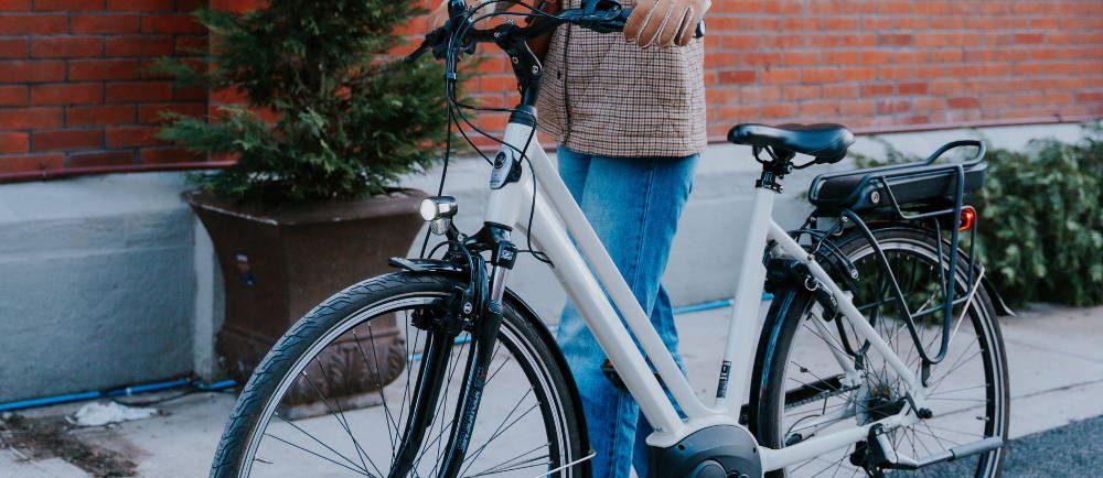 a woman standing next to Gazelle Medeo electric city bike