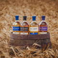 Bouteilles de Single Malt Scotch Whisky posées sur un fût en bois dans un champ d'orge de la distillerie Kilchoman sur l'île d'Islay dans les Hébrides intérieures d'Ecosse