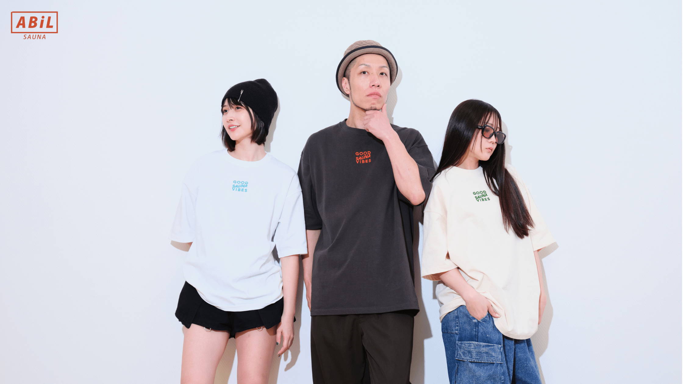 ビッグシルエットが映えるGOOD SAUNA VIBES Teeを着た男女モデル夏にぴったりなABiLのABiYO? Tシャツを着た男性モデルの着用イメージ外気浴スペースで目を閉じて“ととのい”を感じている女性