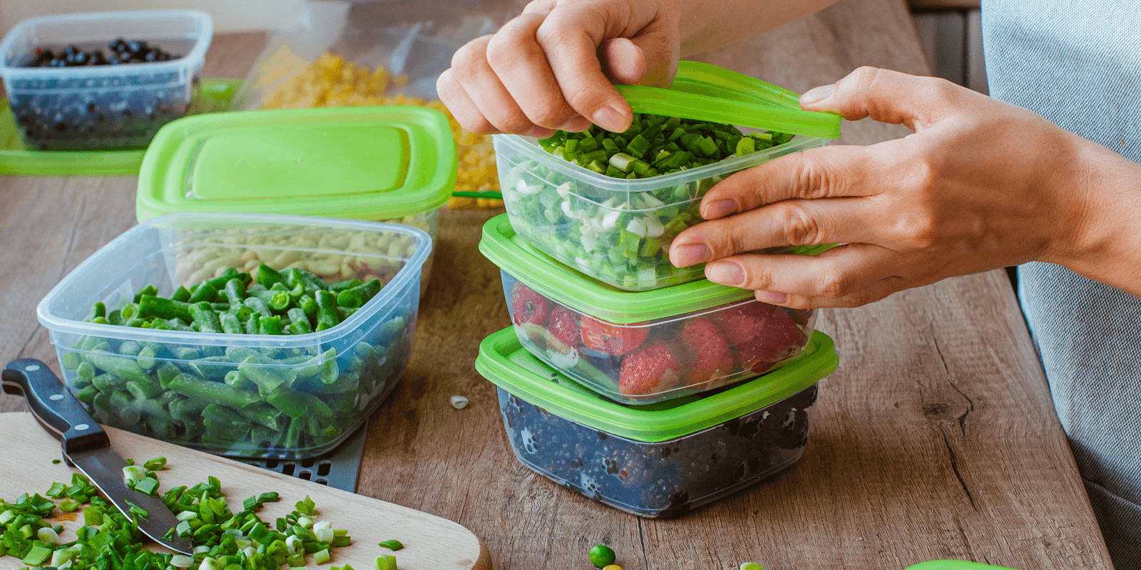 Person closing containers with fresh fruits and vegetables.