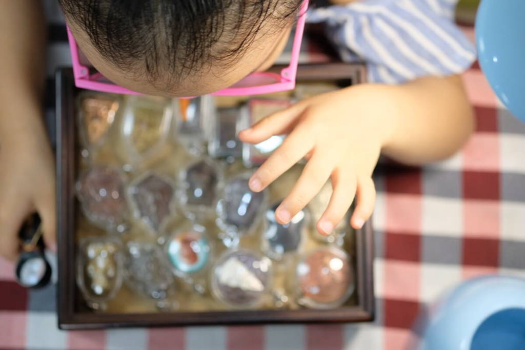 Little girl exploring contents inside a sensory bin.
