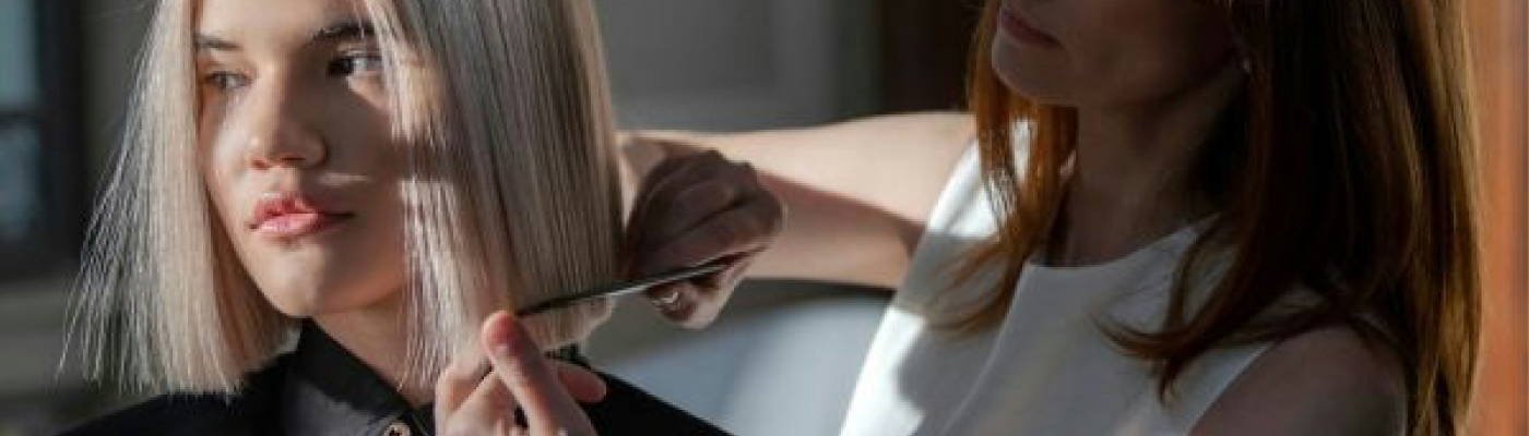 blonde woman getting a haircut by a woman with longer red hair