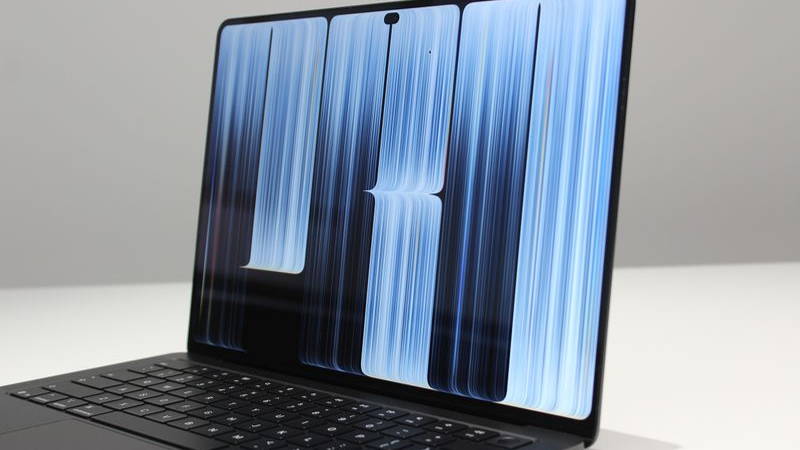 Photograph of 2,000-Nit OLED in Apple’s New MacBook. Laptop flipped open with blue screensaver.