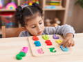 Toddler concentrating on a colorful wooden number puzzle while matching pieces at a Montessori-style play table