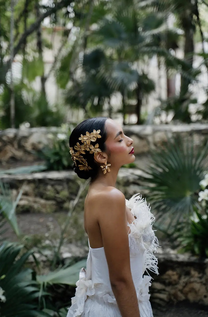 Une belle femme mexicaine aux cheveux noirs coiffés en chignon marchant à travers les ruines anciennes de Tulum le Cinco de Mayo, entourée d'une végétation luxuriante.