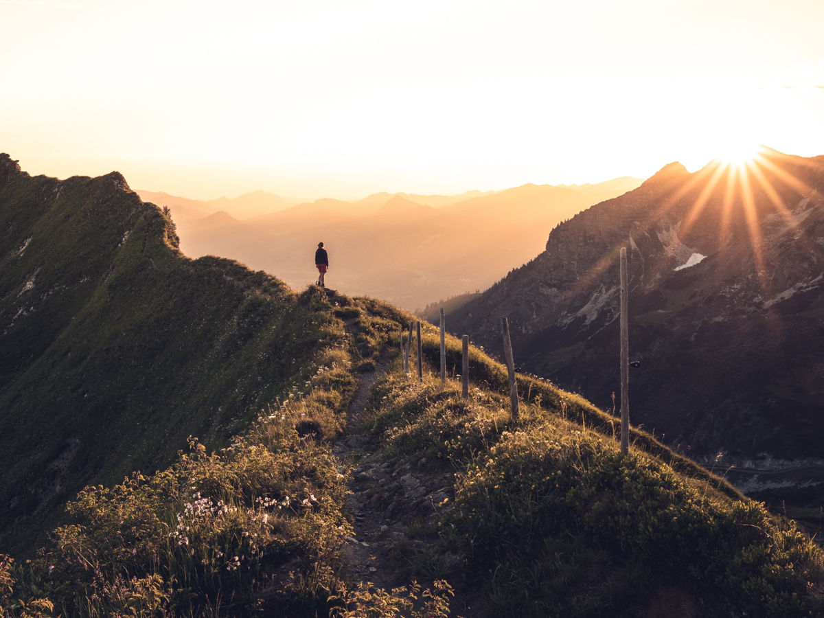 Mensch auf Berggipfel bei Sonnenuntergang