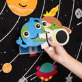 Woman's hand holding space-themed felt cutouts featured in the Montessori Learning Felt Board Space version.