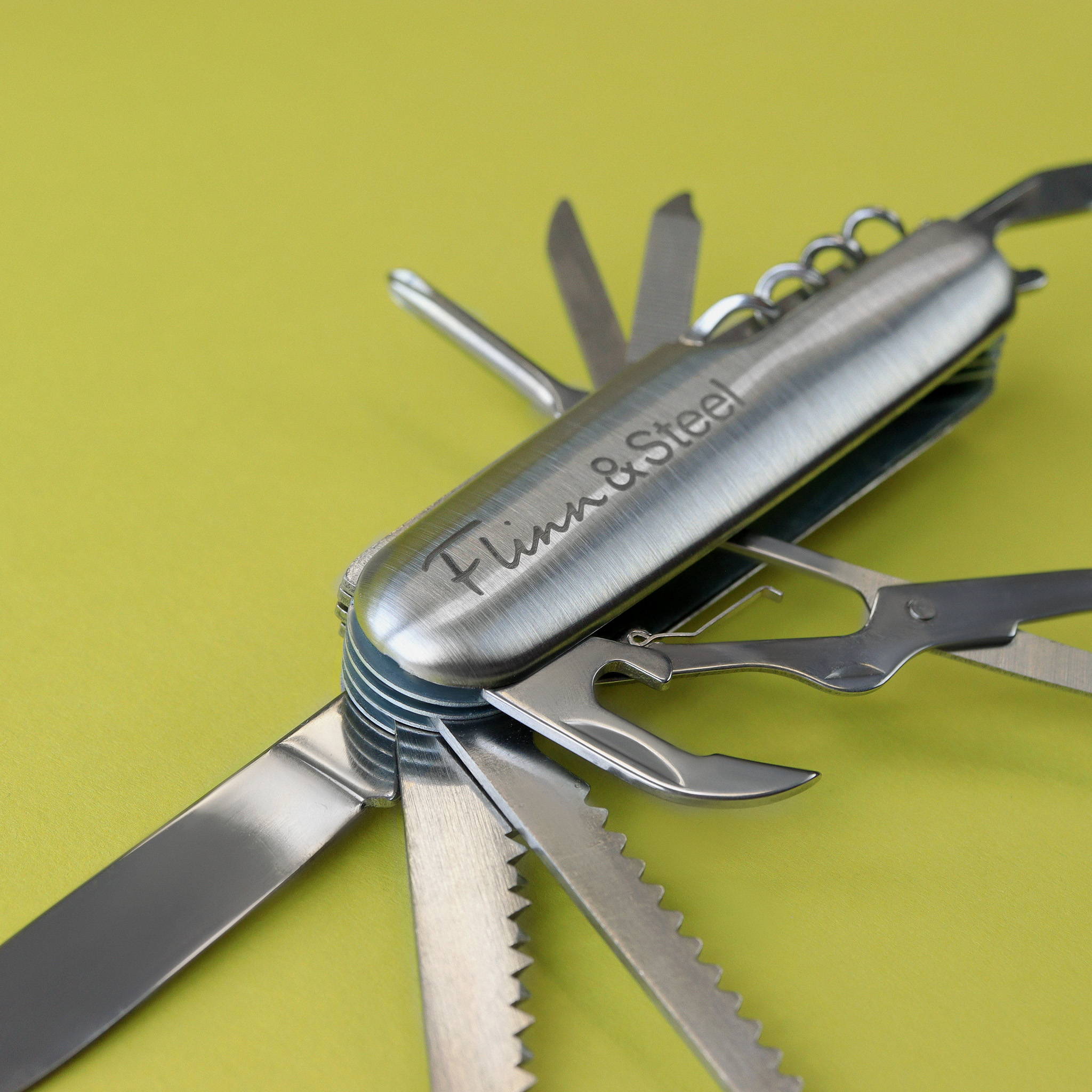 Close up image of a stainless steel multi-tool penknife. All tools can be seen including blade, bottle opener, scissors, file, corkscrew and serrated knife