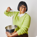 The author of 'Start Here: Instructions for Becoming a Better Cook' holds a whisk above a metal bowl while it drips into it