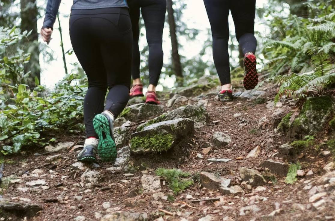 People in black leggings hiking up a trail