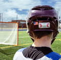 A lacrosse player facing away, with a Tozuda Impact Indicator visible on the back of the maroon helmet.