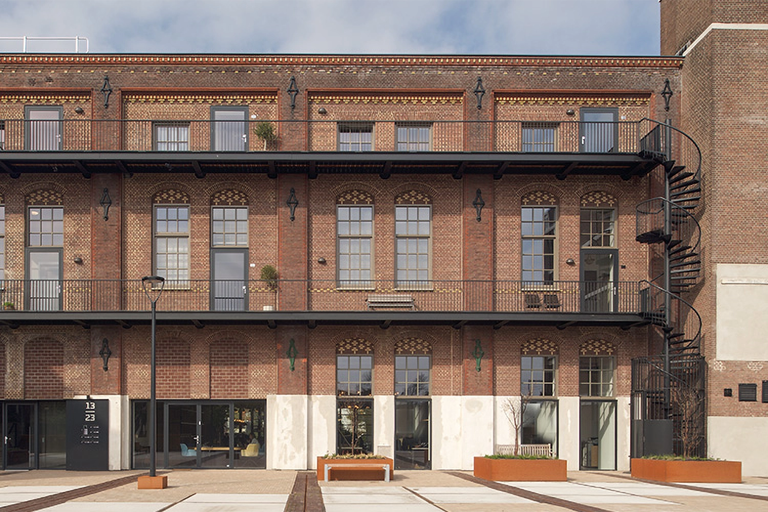 A red brick building on three levels with black balconies