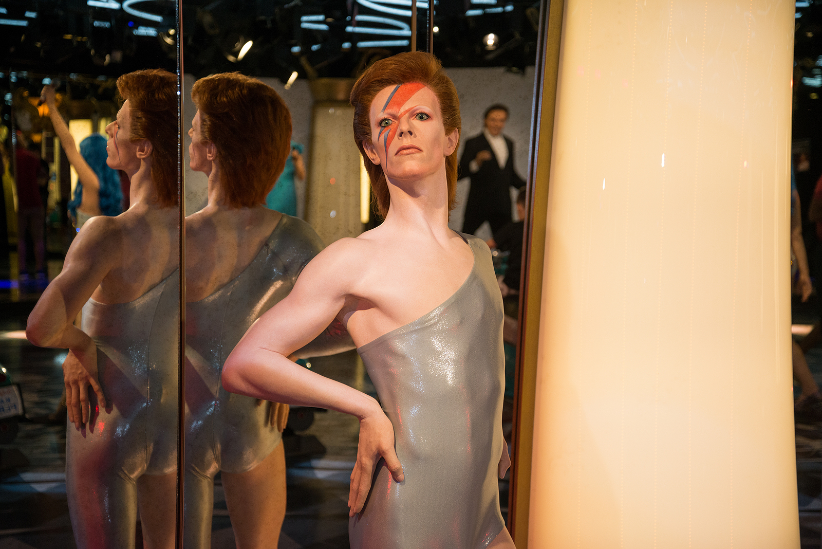 Ziggy Stardust wearing a shiny leotard standing in front of mirrors.