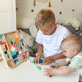 Little boy sitting next to a Montessori Tetris and placing pieces into the wooden Tetris board. 