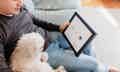 man and small white dog sitting on couch looking at framed keepsake with two blue dog nose prints