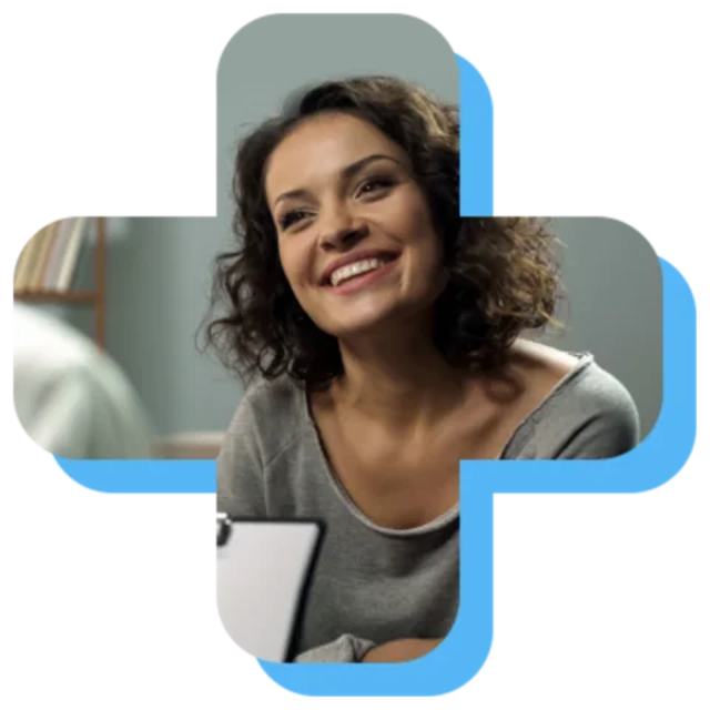 Smiling woman with curly hair engaged in conversation in a casual indoor setting, suggesting a friendly interaction.