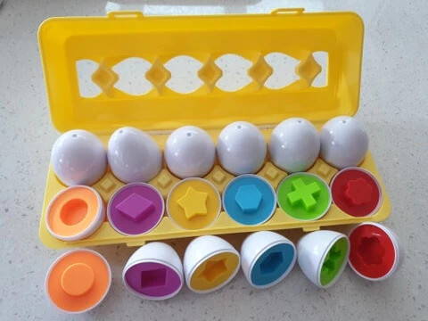 A colorful educational toy for kids with eggs in a carton and different geometric shapes.