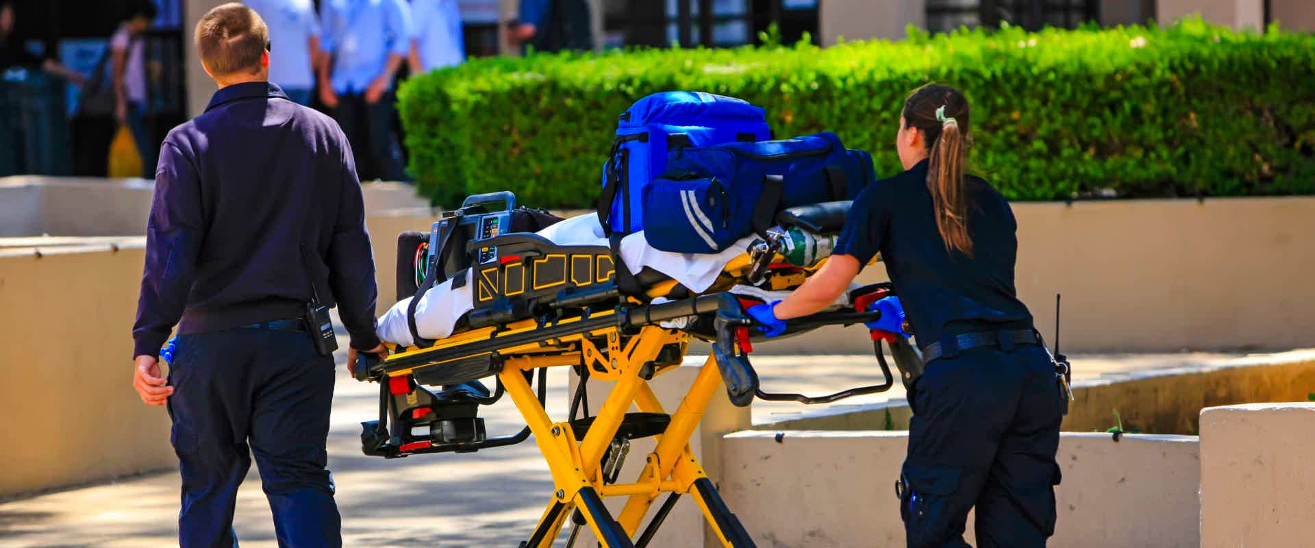 two paramedics pushing an ambulance cot