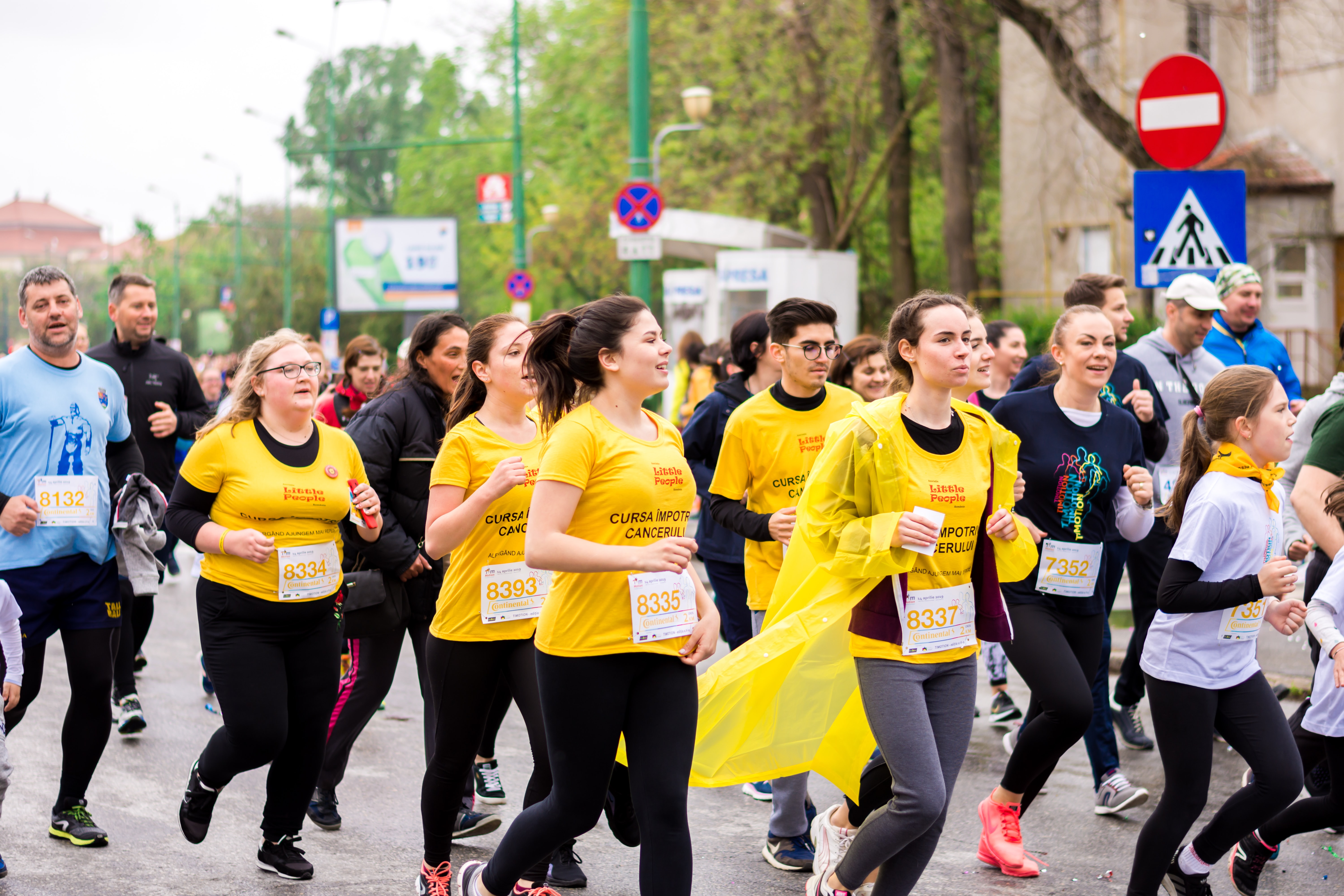 A large group of people wearing the same event shirt run together in a race.