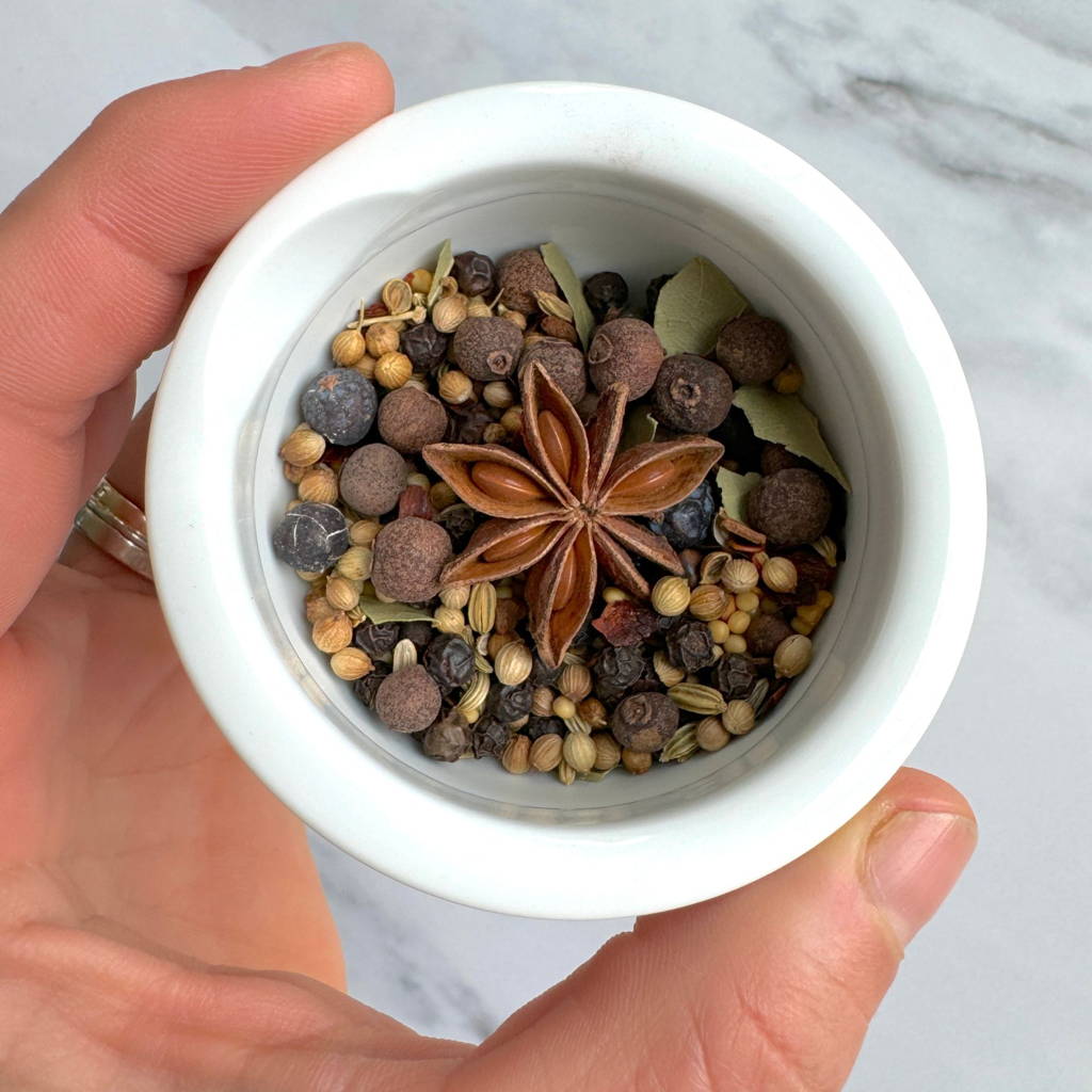 Star anise centers many other pickling spices in a white mortar and pestle
