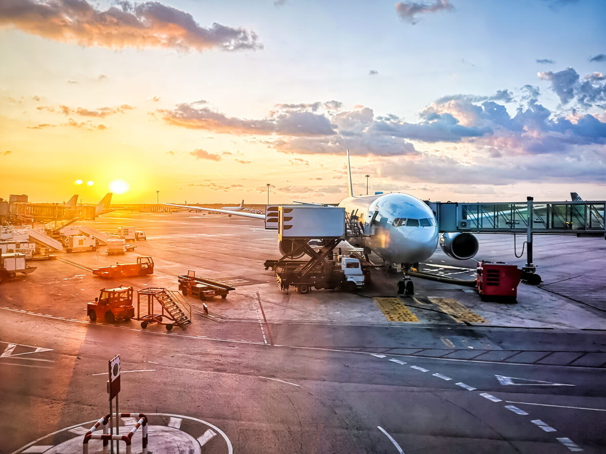 airport sunset with a plane and baggage equipment