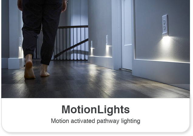 Person walking down hallway at night with multiple motion outlet light covers on wall