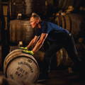 Ouvrier faisant rouler un fût de whisky en bois dans un chai de la distillerie Kilchoman sur l'île d'Islay dans les Hébrides intérieures d'Ecosse
