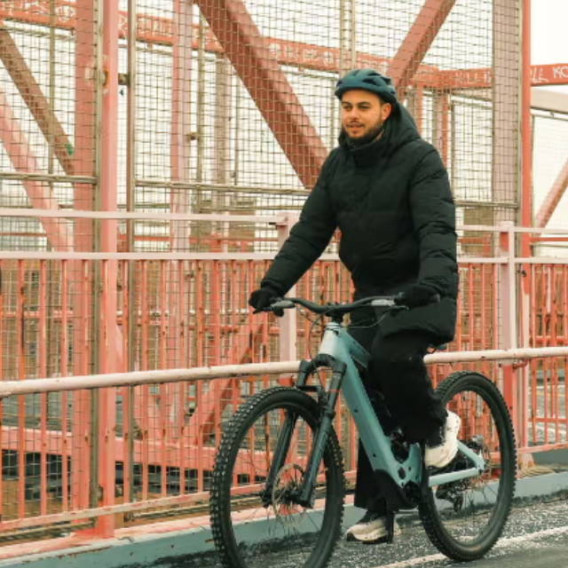 a man riding an electric mountain bike across a bridge in new york city