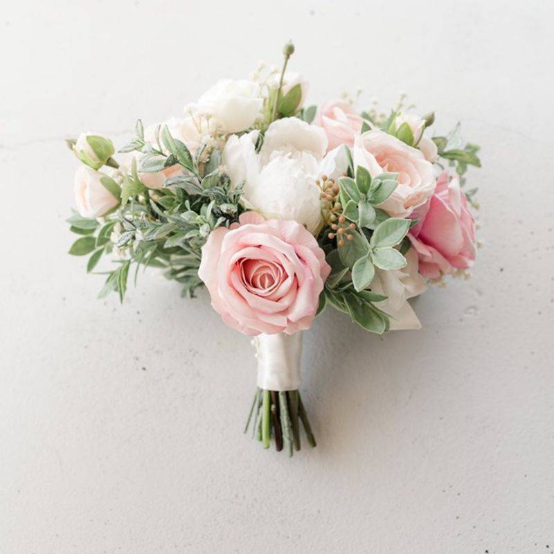 A petite bouquet made of pink roses, blush ranunculus, white peonies, white ranunculus, and boxwood