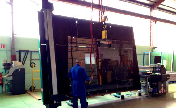 Compagnon vitrier manœuvrant un grand vitrage sur la ligne de fabrication de l’atelier Rossio