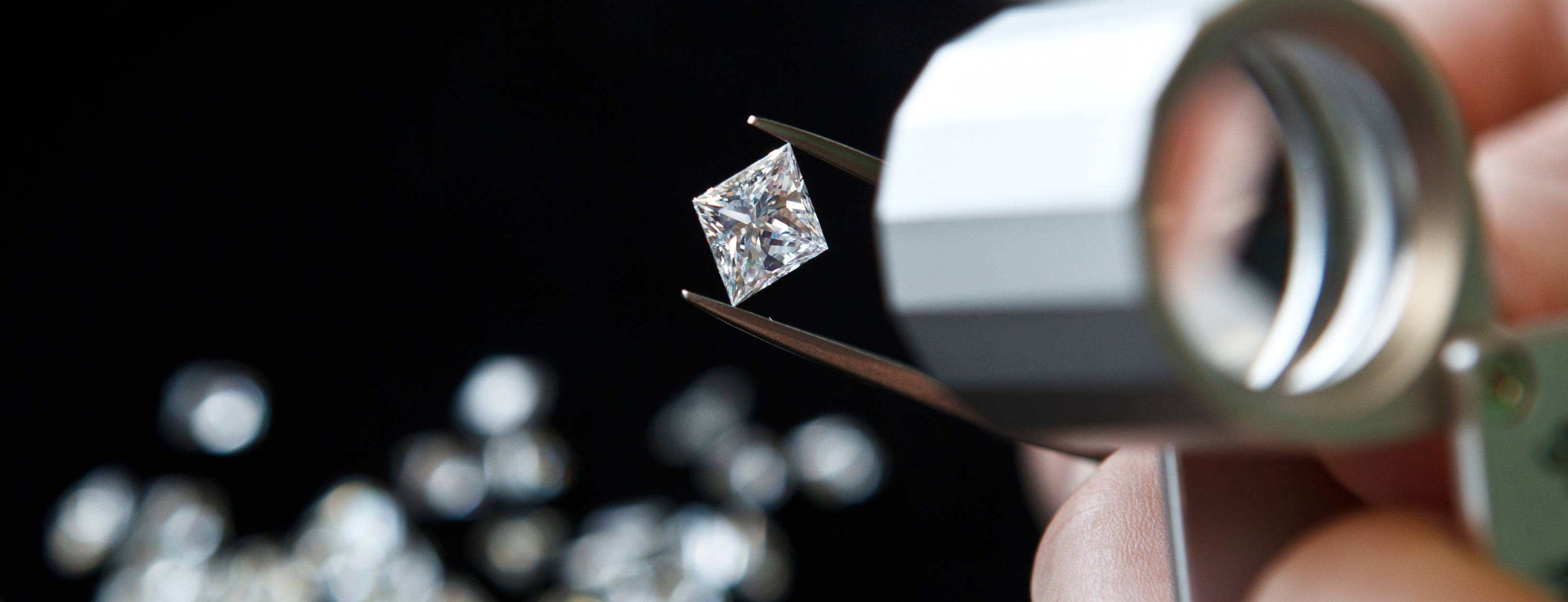 Diamond being held in tweezers and inspected