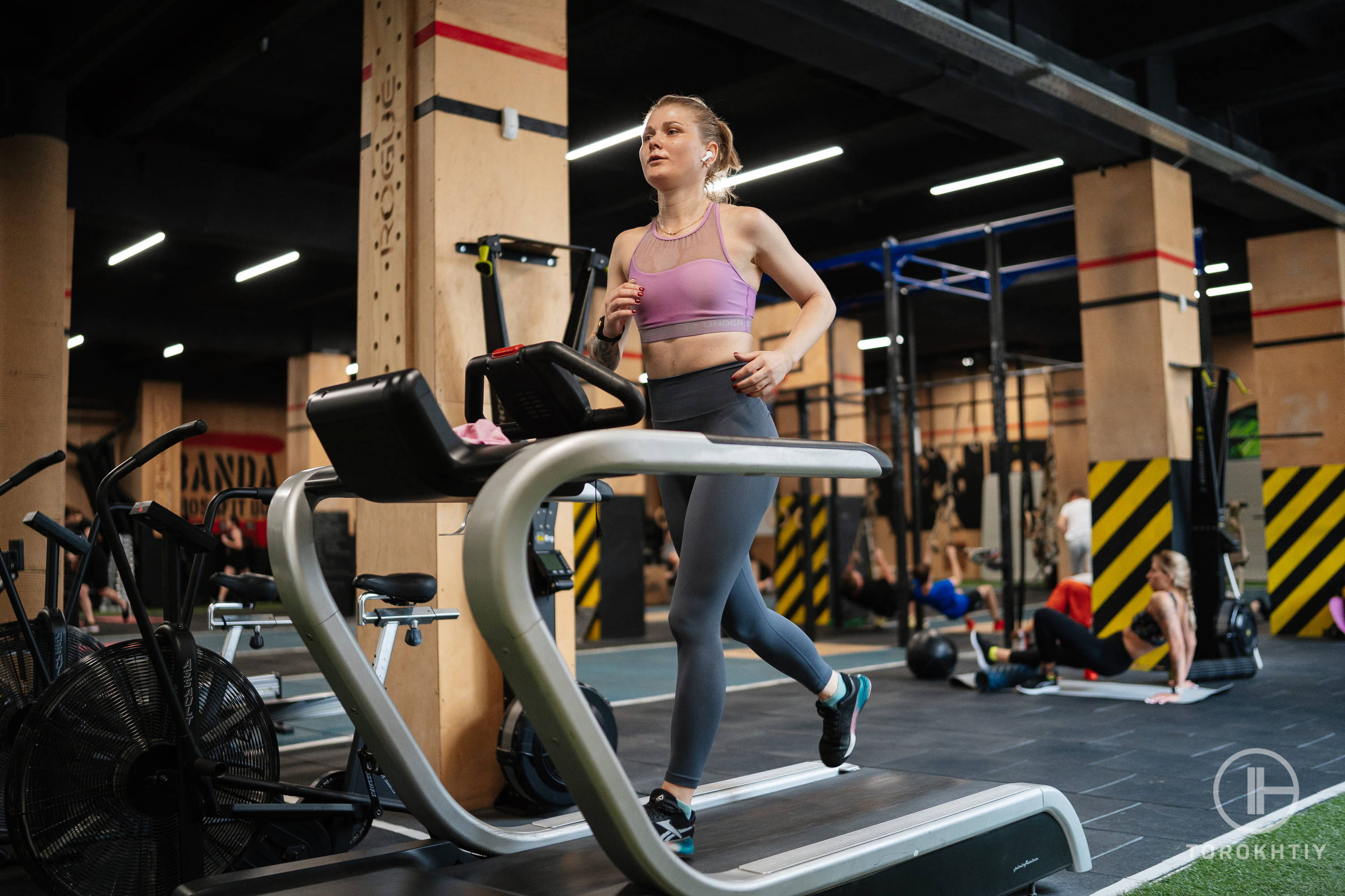 female athlete in pink top running on a treadmill in a gym