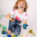 Cheerful boy covered in colorful paint.