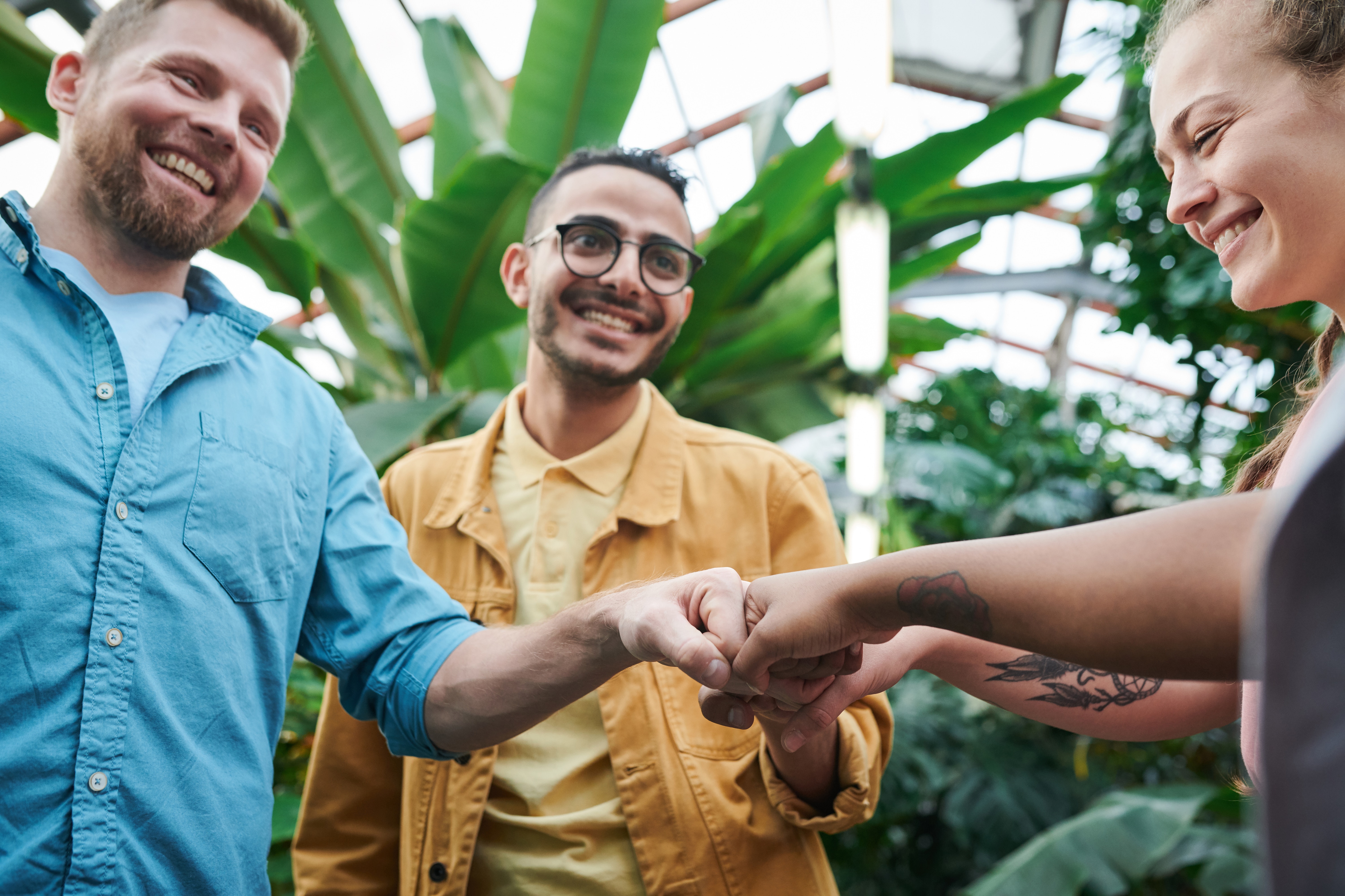 Picture of a man with glasses fist bumping his friends smiling