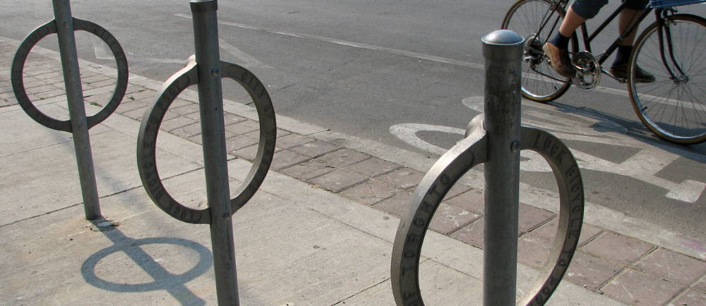 Three bike racks next to bike lane with rider