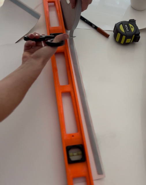 measuring and cutting double sided tape and attaching it to the wallpaper edge