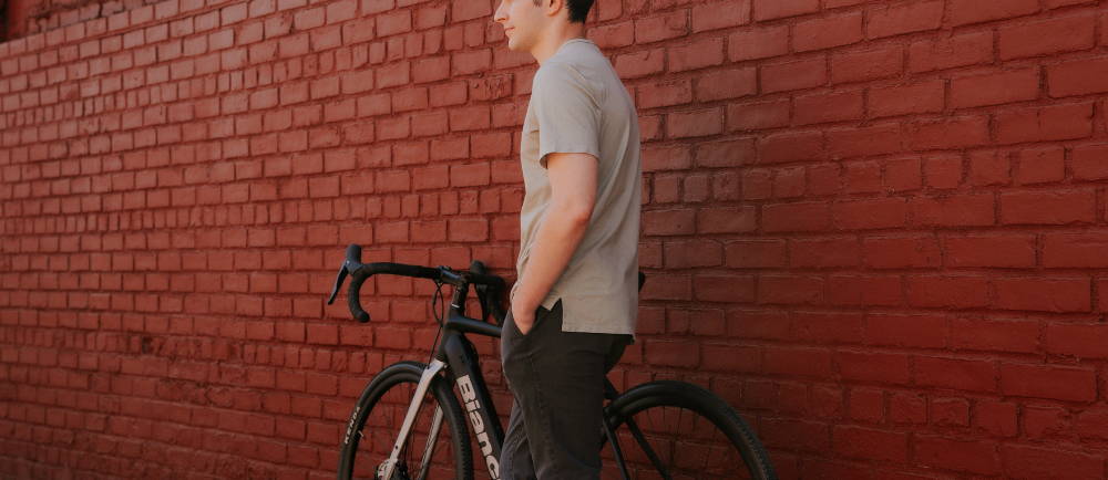 a man standing next to a Bianchi E-Impulso electric road bike in front of a red brick building