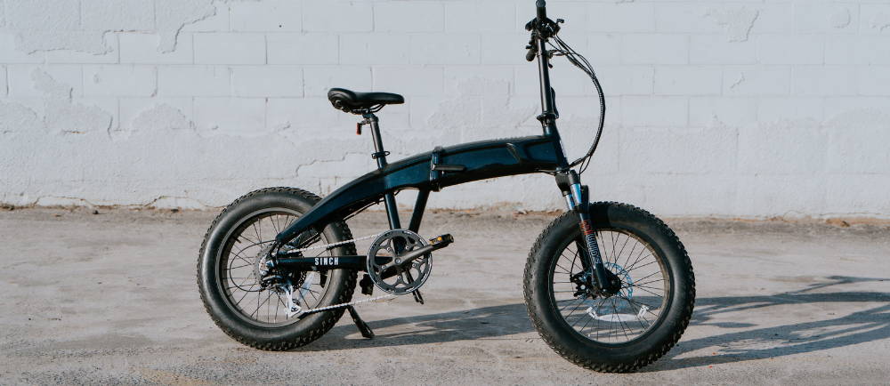 Aventon Sinch electric folding bike in front of white wall