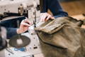 woman sewing the base of a waxed canvas pack