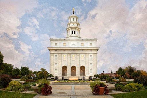 Front view of the Nauvoo Temple standing against a cloudy blue sky.