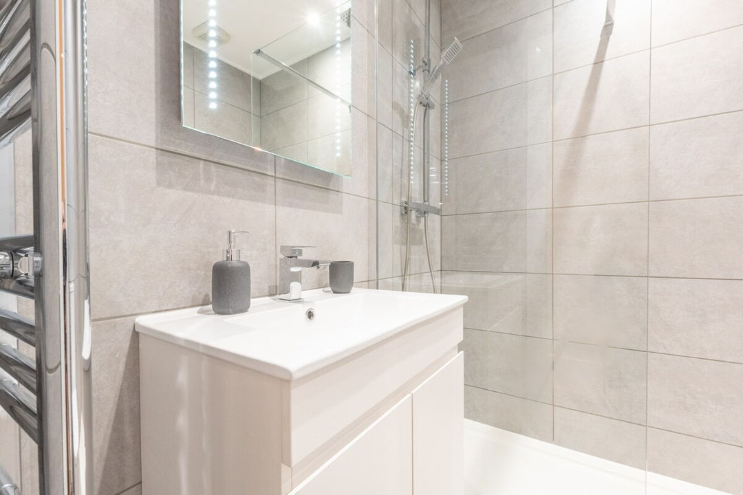 Bathroom showing towel radiator, sink and shower with waterfall showerhead