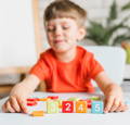 Child using a smart board to arrange colorful number blocks