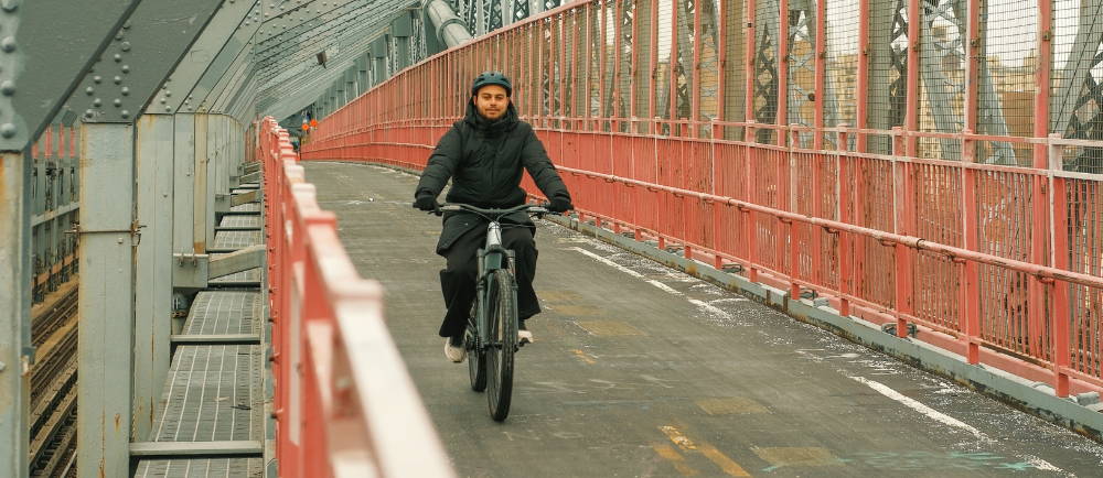 Guy riding an e-bike over a bridge