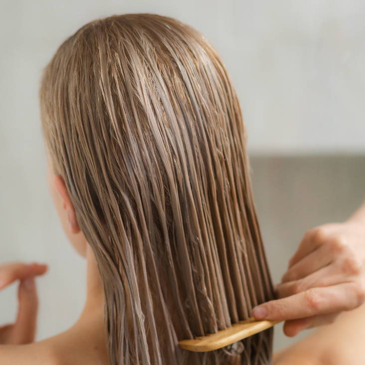 shoulder-length wet, blonde hair being combed