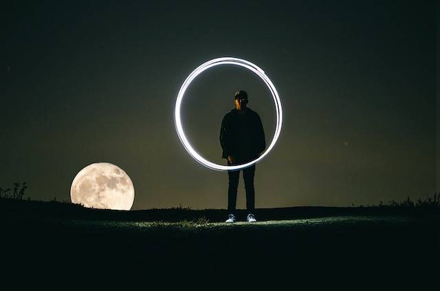 un ragazzo compie un cerchio in aria con una torcia. Fotografato con la tecnica del light painting e lunga esposizione