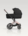 Black Cybex Priam Fold Lux carry cot on the Rosegold frame of the stroller, in front of a White Studio Background.